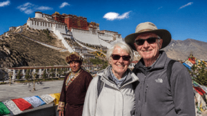 A senior couple enjoying Tibet tours for seniors standing in front of the Potala Palace in Lhasa with their local guide