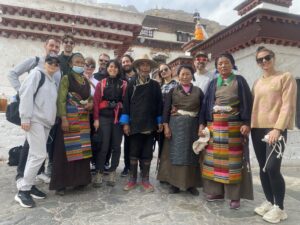 Solo travelers group at ancient Tibetan monastery with traditional architecture and local guides