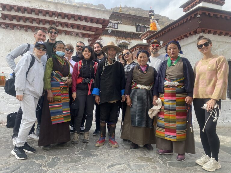 Solo travelers group at ancient Tibetan monastery with traditional architecture and local guides