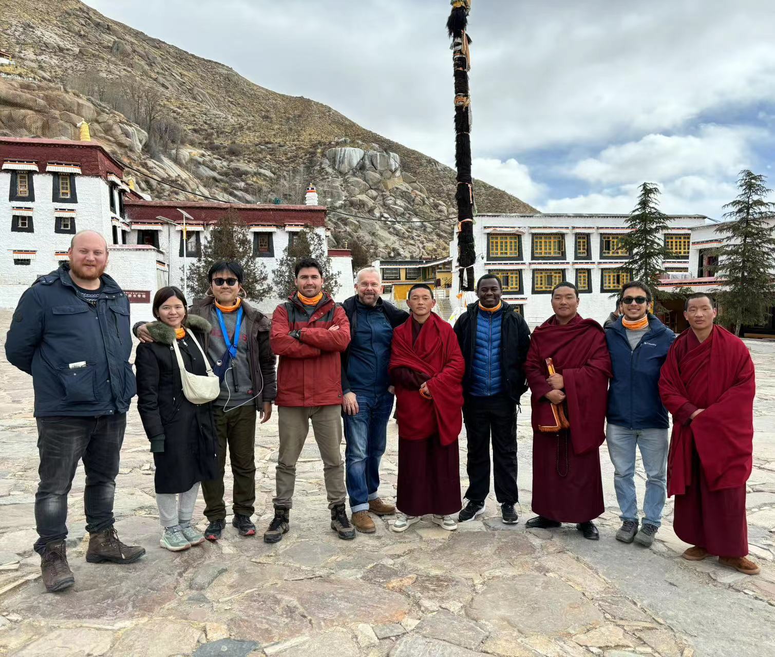 Large Solo Travelers Group at Sacred Tibetan Monastery Large group of diverse solo travelers posing at sacred Tibetan monastery with white-washed traditional walls