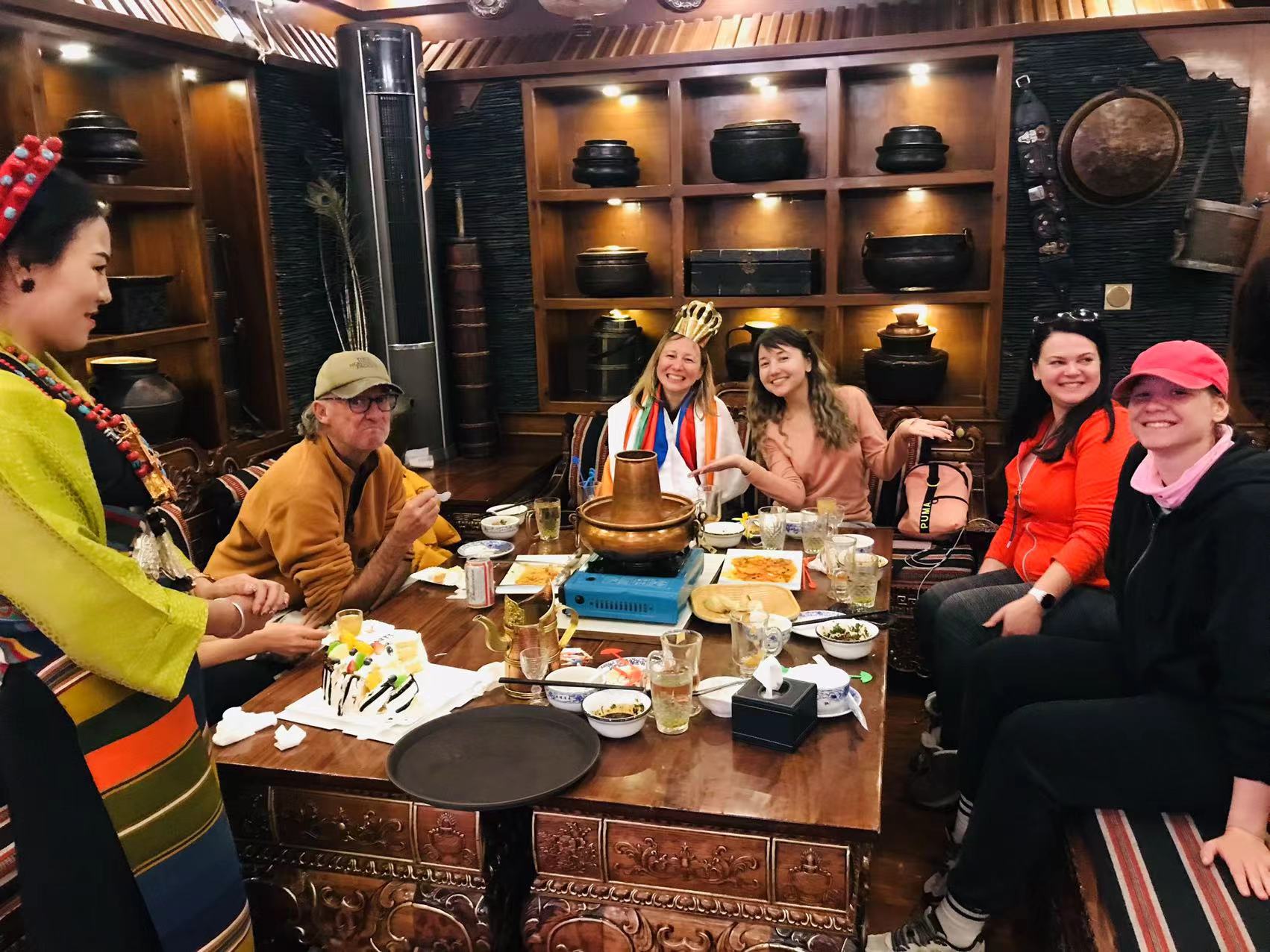 Solo Travelers Evening Social Gathering in Tibetan Hotel Setting Solo travelers group enjoying evening social gathering in traditional Tibetan hotel lounge setting