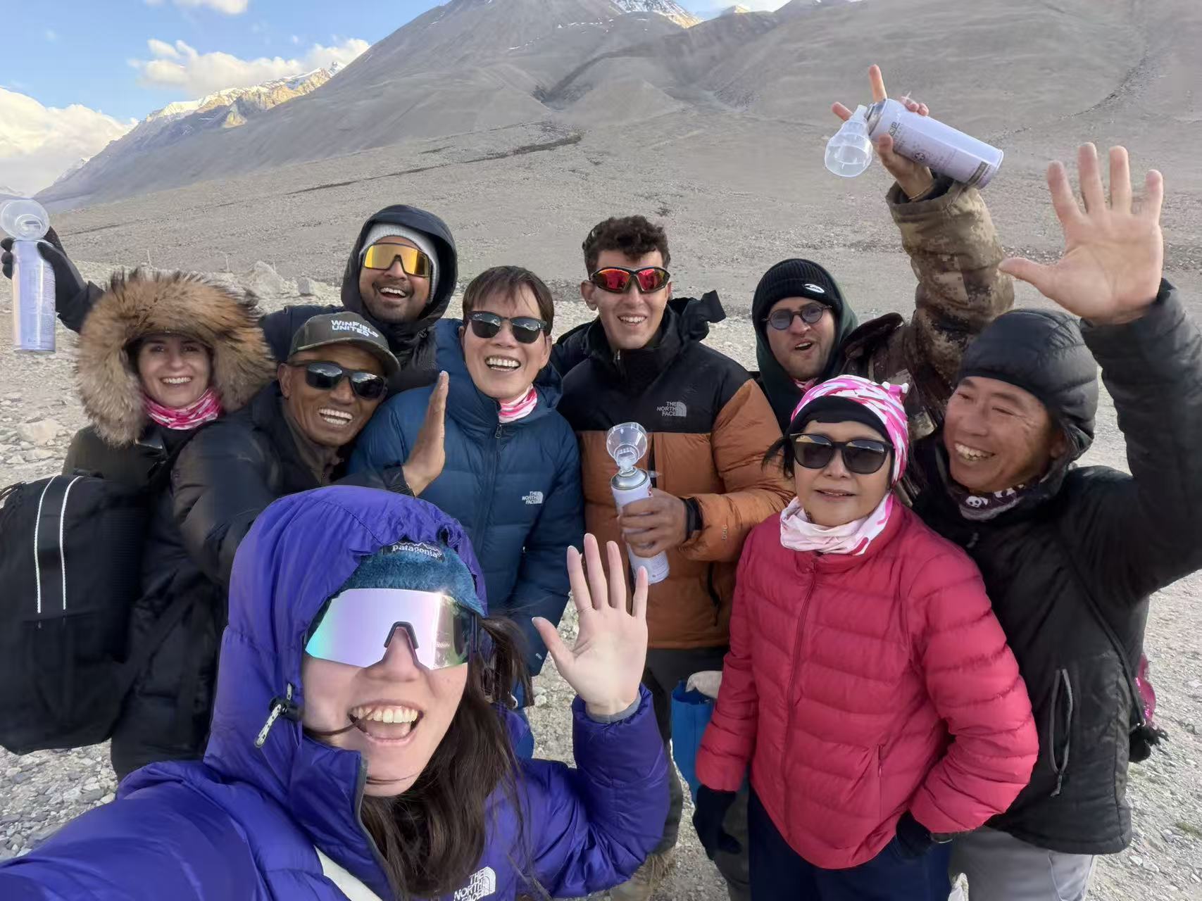 Everest Base Camp Group Victory and Safety Tibet Happy group of travelers and local Tibetan guides celebrating at Everest Base Camp North during a Tibet trekking tour.