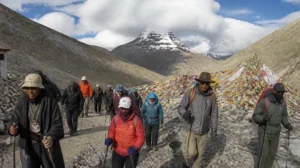 Pilgrims trekking the sacred Kora circuit of Mount Kailash at high altitude with prayer flags and Tibetan mountains in the background
