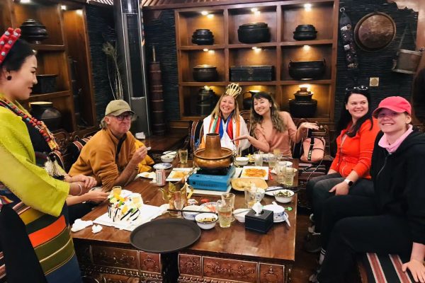 Solo Travelers Evening Social Gathering in Tibetan Hotel Setting Solo travelers group enjoying evening social gathering in traditional Tibetan hotel lounge setting